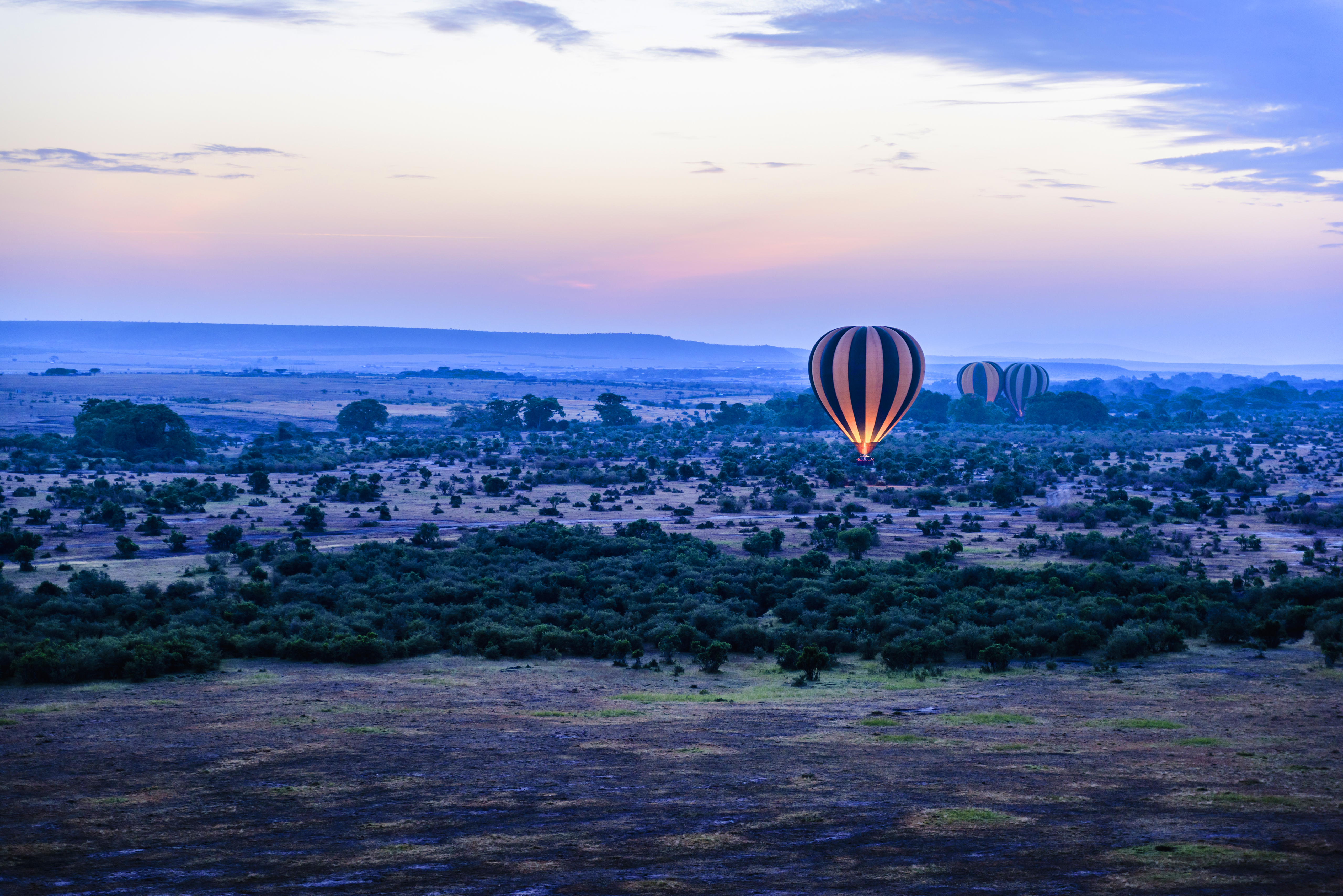 Hot air balloon ascending over the Serengeti at dawn during a Tanzania honeymoon safari with the vast plains and wildlife below