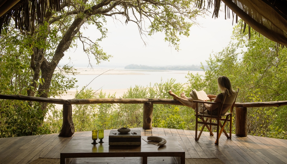 Luxury lodge guests on a private boat safari on the Rufiji River in Tanzania's Nyerere National Park at dawn with hippos and waterbirds visible